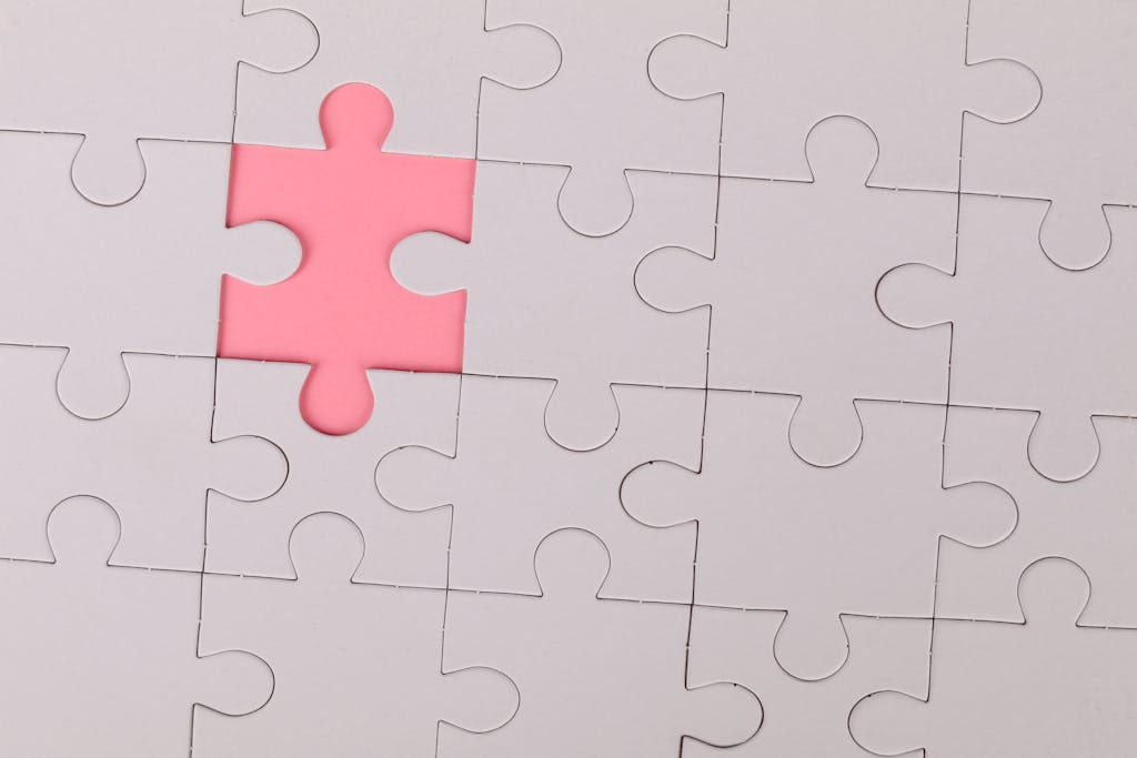 Close-up of an unfinished puzzle with a pink missing piece, highlighting emptiness.